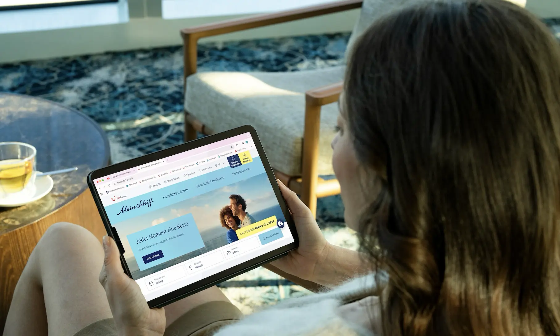 Frau sucht auf Tablet nach Mein Schiff Kreuzfahrten